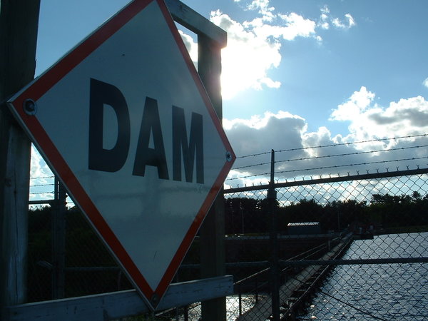 A photograph of a DAM warning sign on the edge of a dam